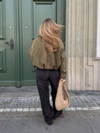 Woman wearing a faux suede collared bomber jacket, side angle